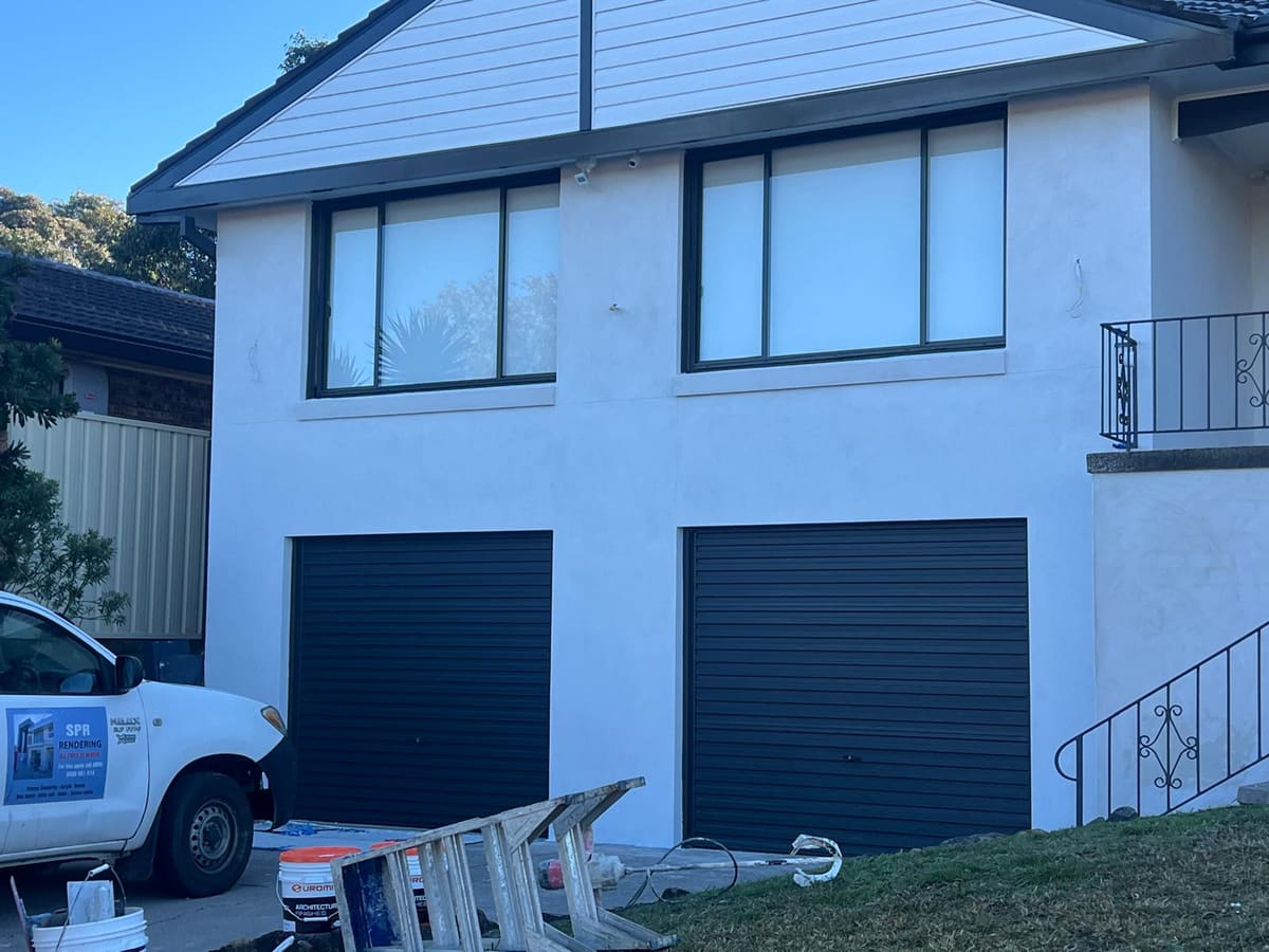 White rendered double garage frontage of a Sydney home with the SPR Rendering work ute parked outside